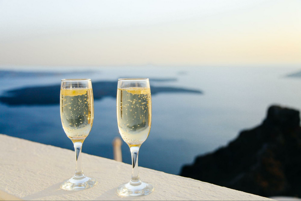 two glasses of champagne on a ledge overlooking a seaside view, as featured in The Wine Movers’ blog on professional wine movers and moving a wine collection