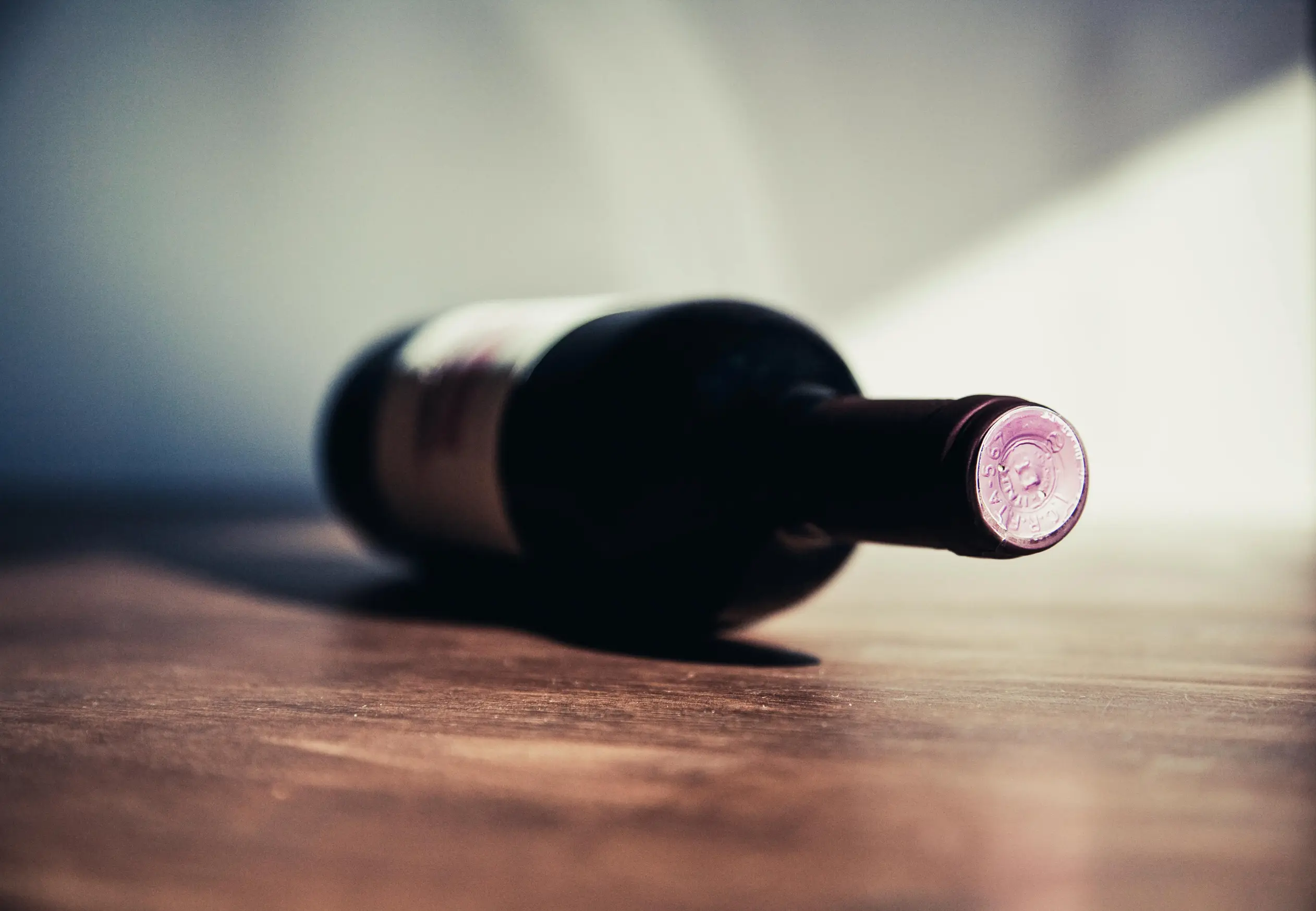 a bottle of wine lying in the table with a blur background